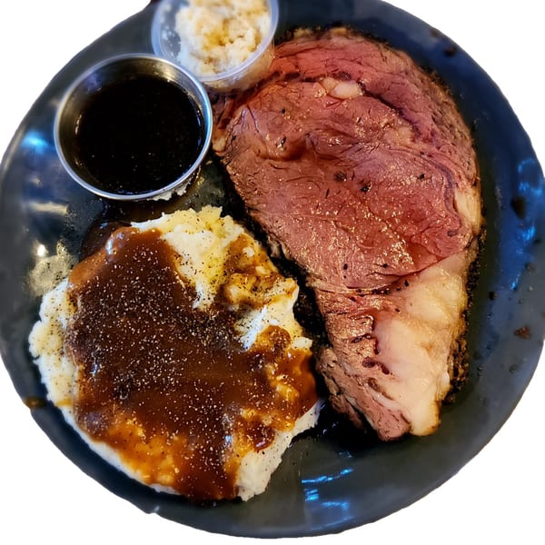 Brewgards Lounge's prime rib with mashed potatoes, gravy, and horseradish on a black plate.