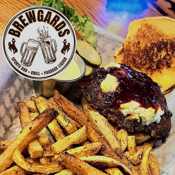 Brewgards Lounge burger with BBQ sauce, fries, pickles, and a side of dipping sauce.