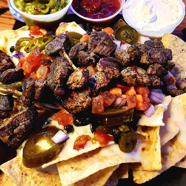 Brewgards Lounge steak nachos with jalapeños, tomatoes, onions, and three dipping sauces.