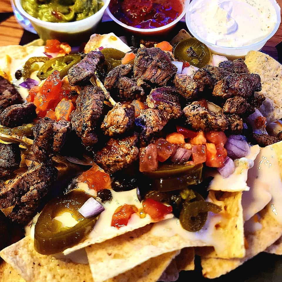 Brewgards Lounge steak nachos with jalapeños, tomatoes, onions, and three dipping sauces.