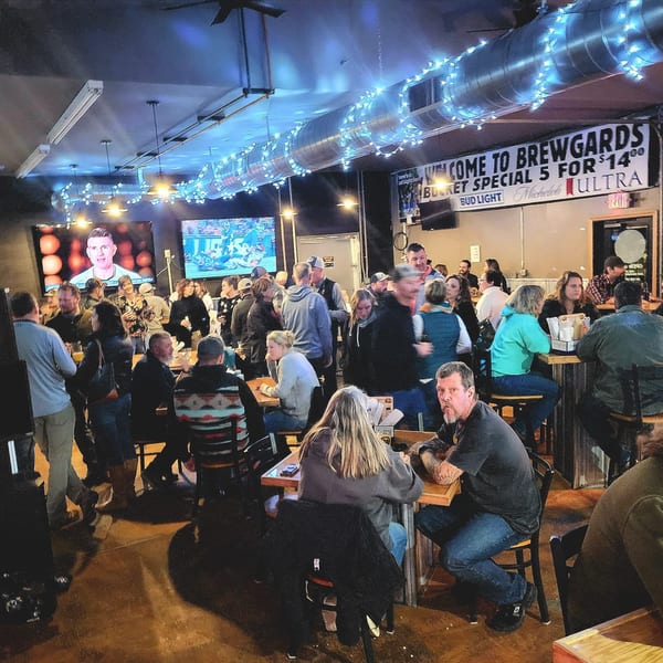 Brewgards Lounge filled with patrons watching sports on large screens and socializing at tables and the bar.