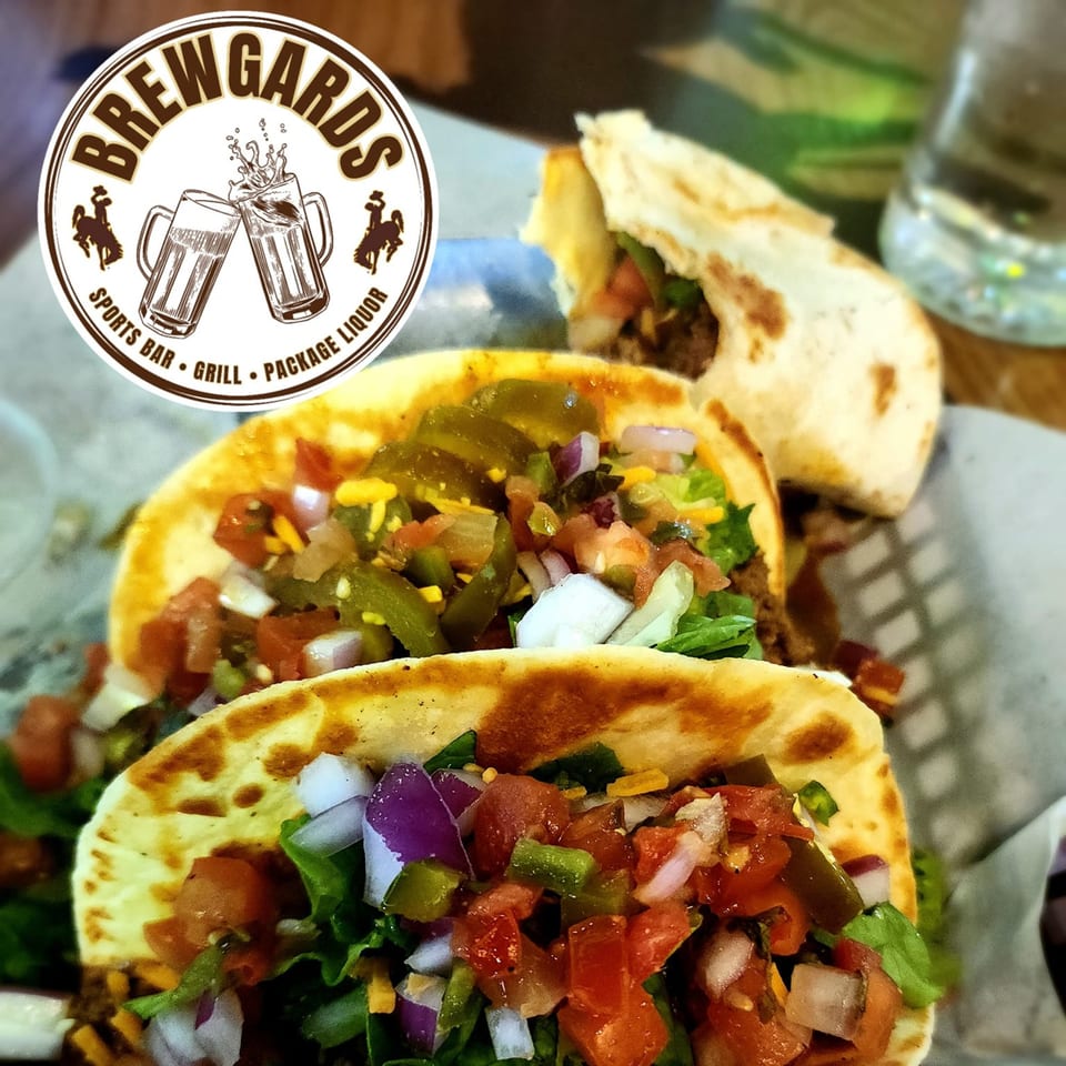 Three Brewgards Lounge soft tacos filled with meat, lettuce, cheese, tomatoes, onions, and jalapeños.