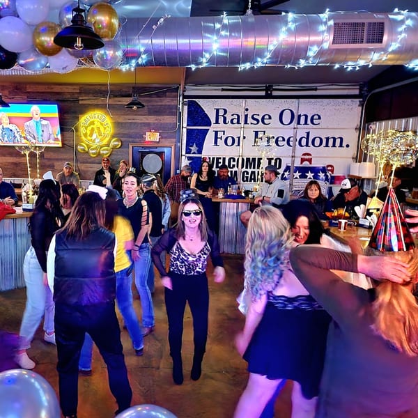 Patrons dancing and socializing in a lively bar-and-grill, decorated with balloons and string lights.