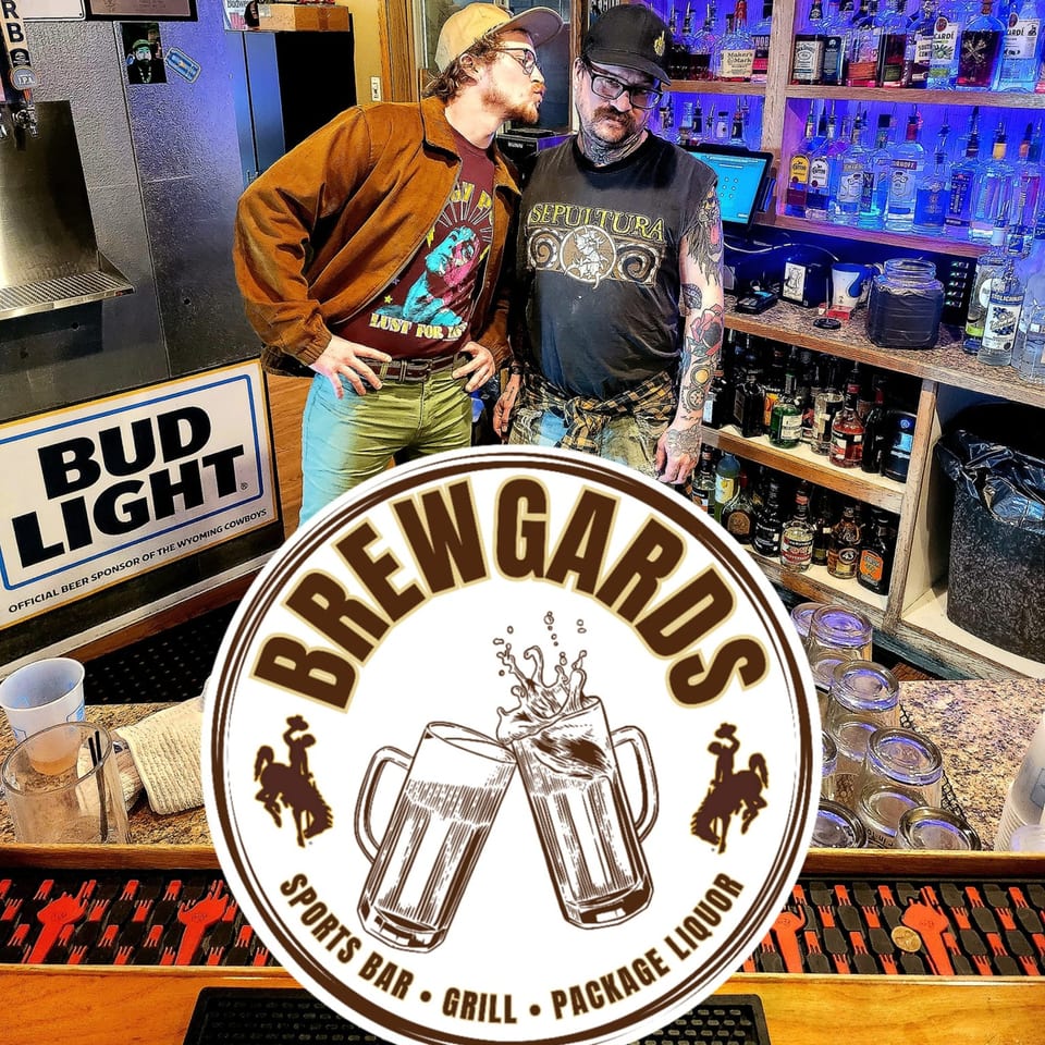 Two men pose playfully in front of a well-stocked bar at Brewgards Lounge, with the logo overlaid.