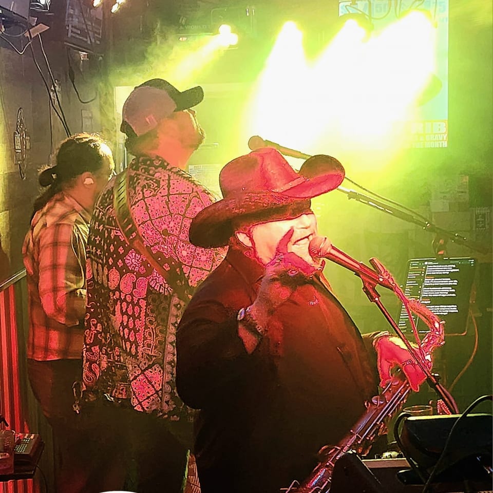 A band performs live at Brewgards Lounge, with a singer in a cowboy hat at the microphone.