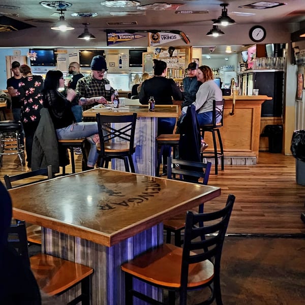 Patrons enjoying food and drinks at tables and a bar in Brewgards Lounge, a bar-and-grill.