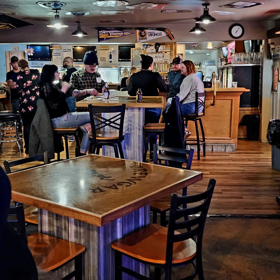Patrons enjoying food and drinks at tables and a bar in Brewgards Lounge, a bar-and-grill.