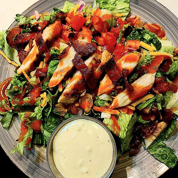 Brewgards Lounge's BBQ chicken salad with bacon, tomatoes, cheese, and a side of ranch dressing.